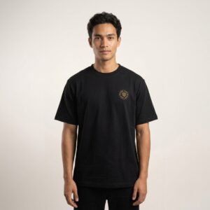 Shop the AMOGA black t-shirt with a small circular emblem chest print in gold and black. Premium cotton, relaxed fit, minimal streetwear tee.